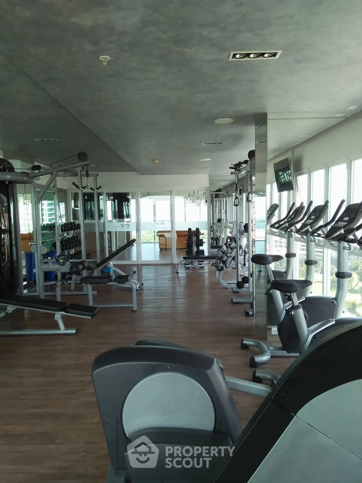 Spacious gym with modern equipment and panoramic city views, perfect for fitness enthusiasts.