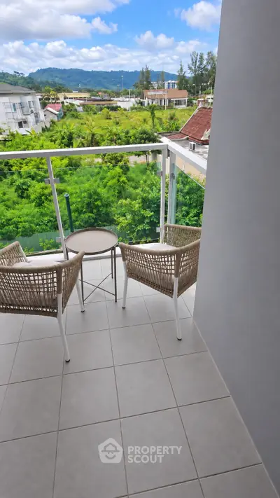 Charming balcony with scenic view of lush greenery and distant hills, perfect for relaxation.