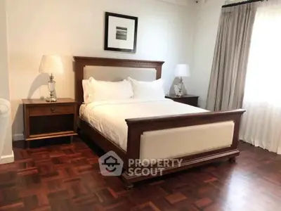 Elegant bedroom with classic wooden bed and parquet flooring, perfect for a cozy retreat.