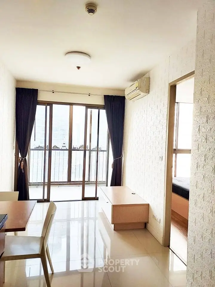 Bright living room with large windows and balcony access in modern apartment.