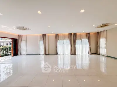 Spacious and bright living room with large windows and elegant curtains, perfect for modern living.