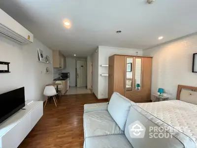 Modern studio apartment with integrated living space, featuring sleek furnishings, hardwood flooring, and a compact kitchenette for urban living.