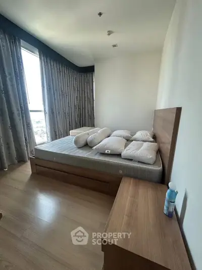 Spacious bedroom with modern wooden furniture and large window view