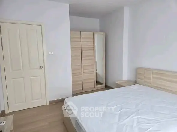 Spacious bedroom with modern wooden furniture and ample natural light.