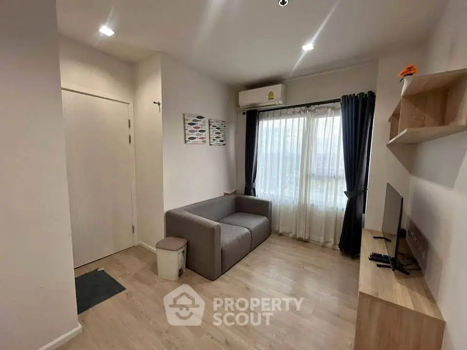 Cozy living room with modern decor, featuring a comfortable sofa and natural light from large window.