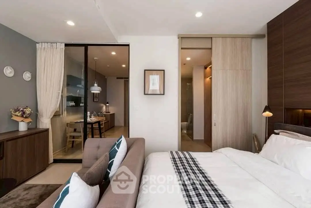 Modern bedroom with stylish decor and open layout to dining area, featuring elegant furnishings.