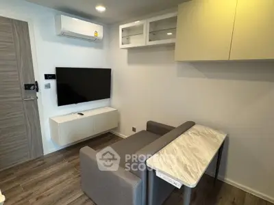 Modern living room with sleek furniture and wall-mounted TV, featuring air conditioning and stylish cabinetry.