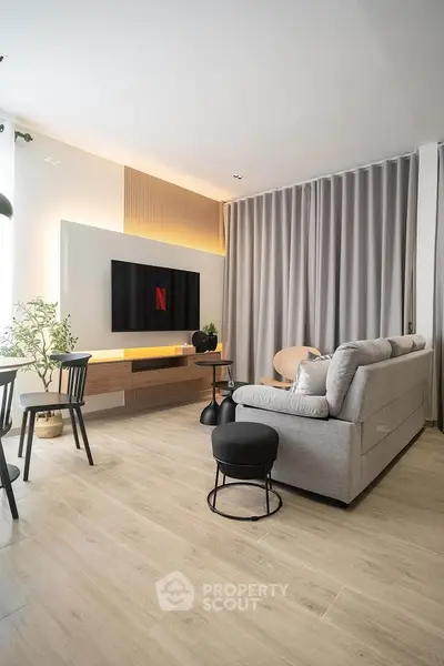 Modern living room with stylish decor and large TV, perfect for entertainment.