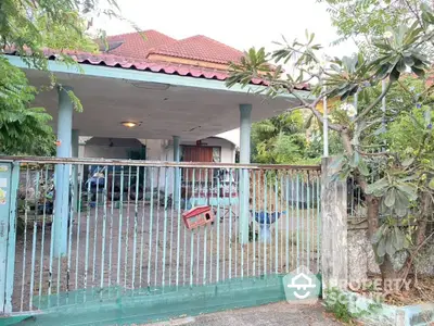 Charming single-story home with a spacious carport and lush greenery, nestled behind a secure gated entrance, offering privacy and tranquility.