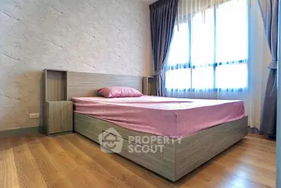 Modern bedroom with wooden flooring and stylish bed frame in natural light.