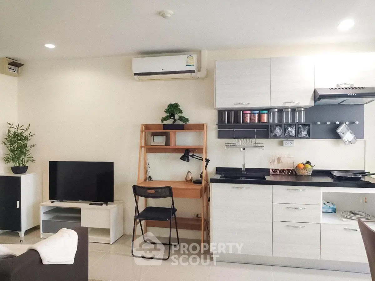 Modern studio apartment with sleek kitchen and cozy living area, featuring air conditioning and stylish decor.