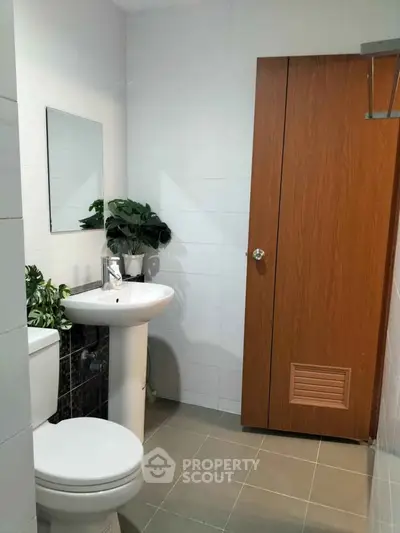 Modern bathroom with sleek pedestal sink and wooden cabinet