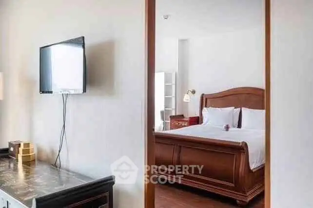 Elegant bedroom with wooden bed frame and wall-mounted TV, perfect for relaxation.