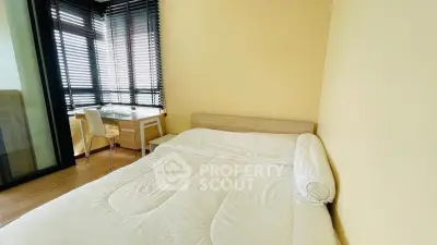 Cozy bedroom with large windows and natural light, featuring a comfortable bed and a small study area.