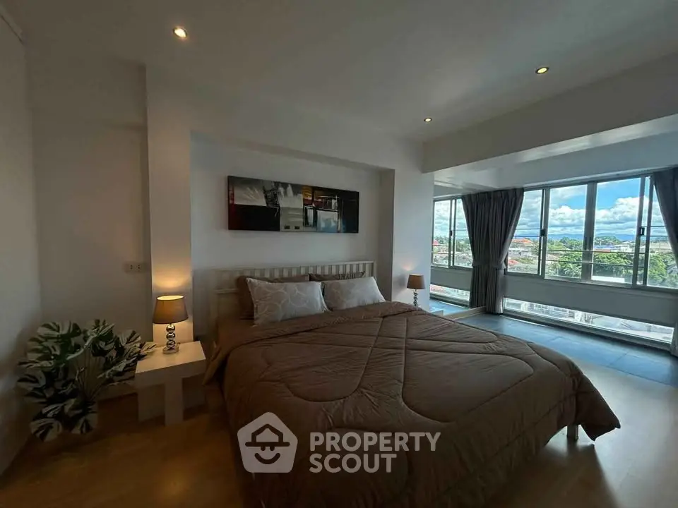 Spacious bedroom with large windows offering stunning views and modern decor.