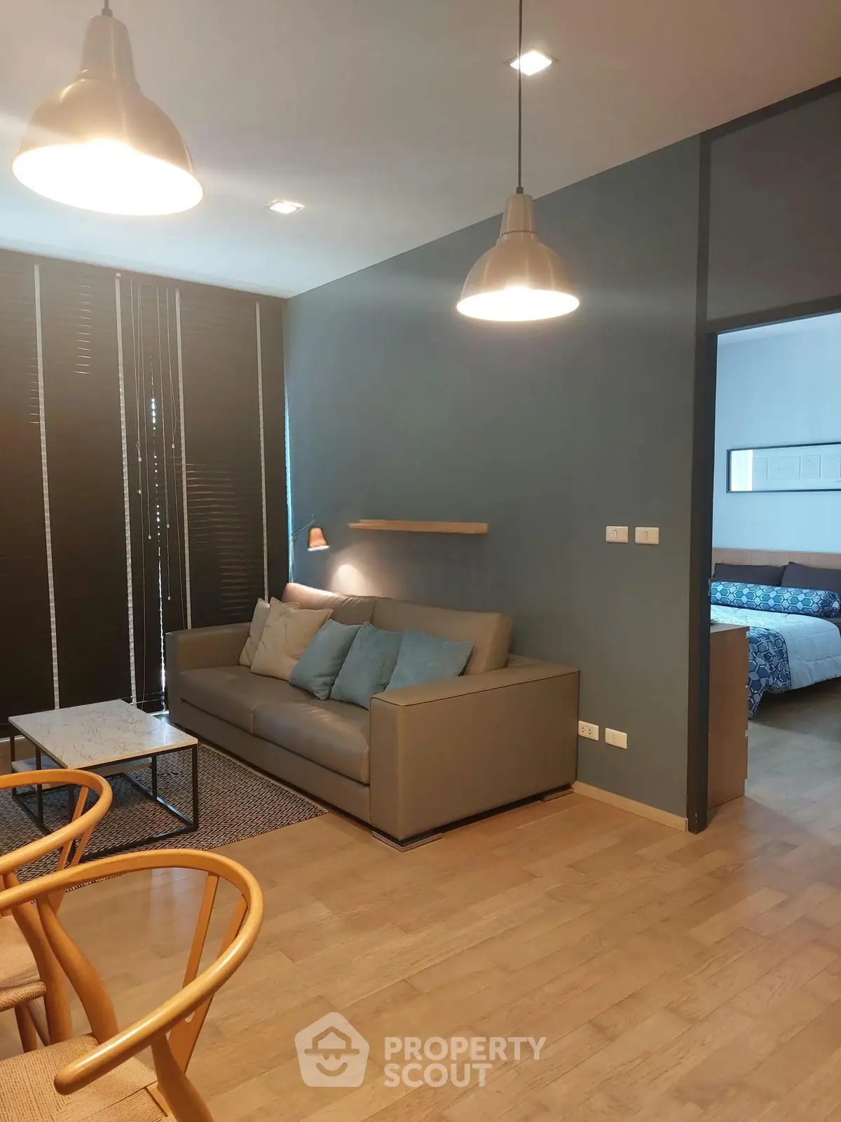 Modern living room with stylish lighting and cozy seating area, adjacent to a bedroom.