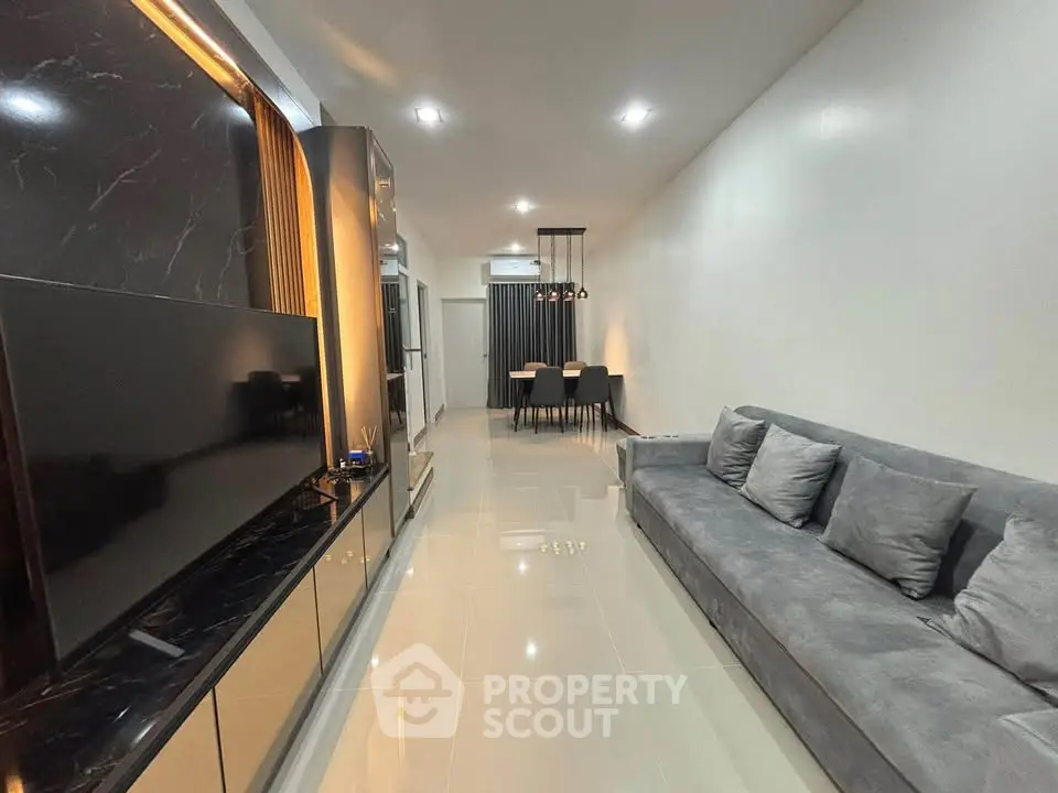 Modern living room with sleek design, featuring a large gray sofa and elegant dining area.