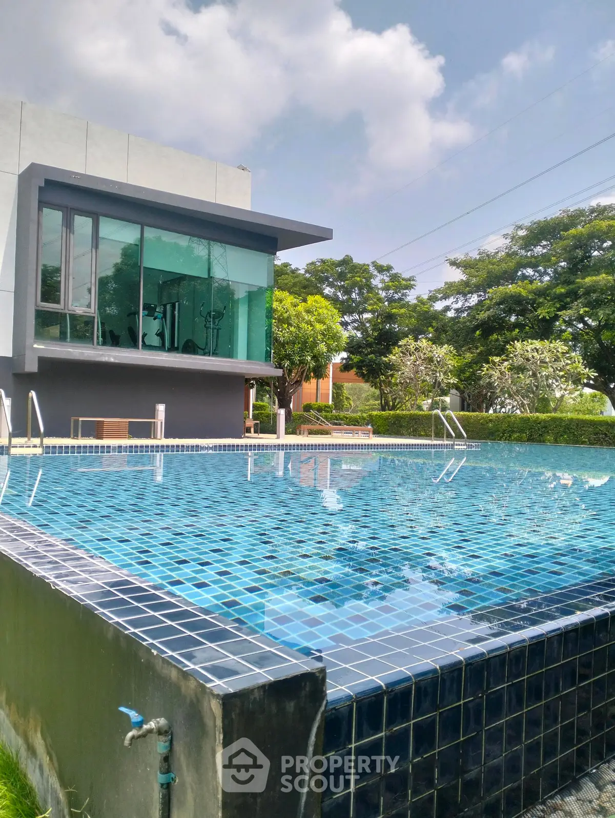 Luxurious modern building with a sparkling outdoor pool and lush greenery, perfect for relaxation and leisure.