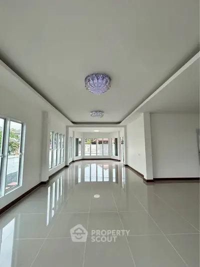 Spacious modern living room with elegant chandeliers and large windows for natural light.