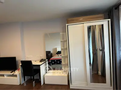 Modern bedroom with sleek furniture and cozy decor, featuring a wardrobe, desk, and TV stand.