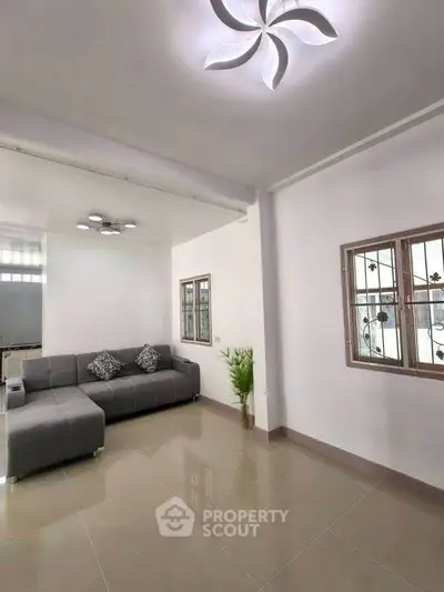 Modern living room with sleek gray sofa and stylish ceiling light fixture.