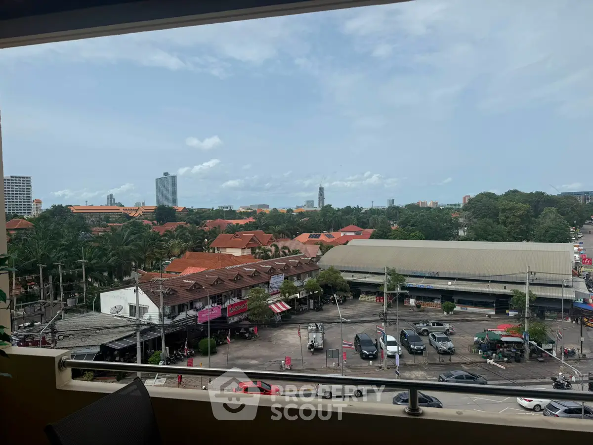 Scenic view from balcony overlooking cityscape with red-roofed buildings and lush greenery.