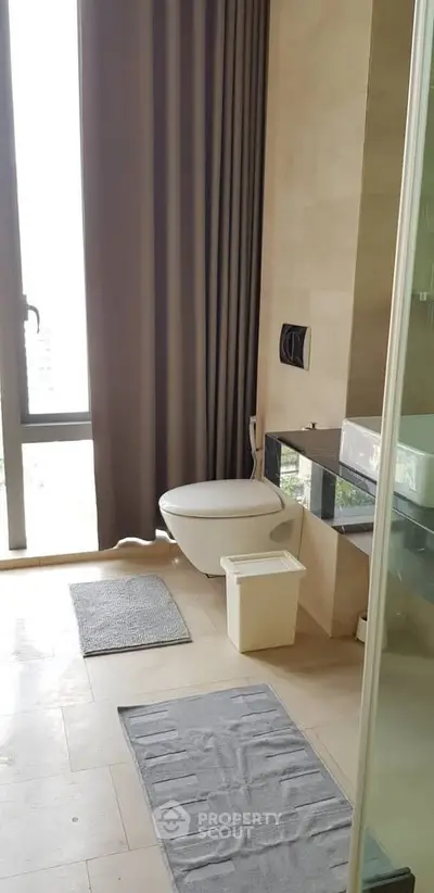Modern bathroom with floor-to-ceiling window and sleek fixtures in a luxury apartment.