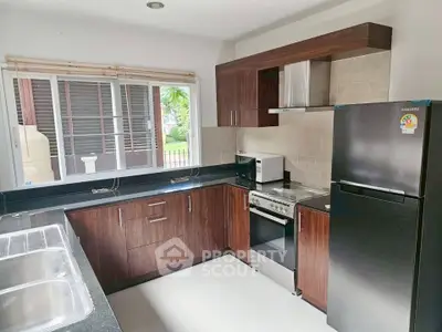 Modern kitchen with sleek appliances and wooden cabinetry, featuring a gas stove and ample natural light.