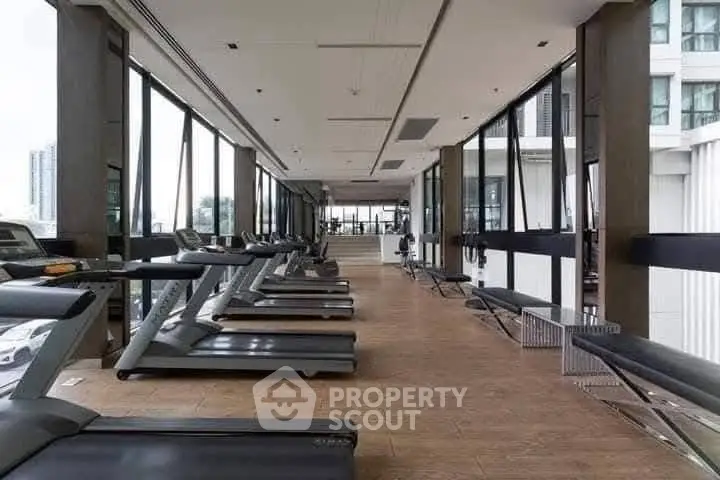 Spacious modern gym with large windows and multiple treadmills in a luxury building.