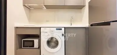 Modern kitchen with washing machine, microwave, and sleek fridge