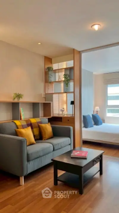 Modern living room with cozy sofa and stylish decor leading to a bright bedroom.