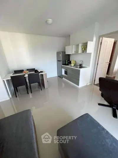 Modern open-plan living room with sleek kitchen and dining area, featuring contemporary furniture and appliances.