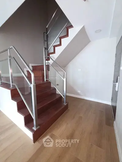 Modern staircase with wooden steps and sleek metal railing in a contemporary home interior.