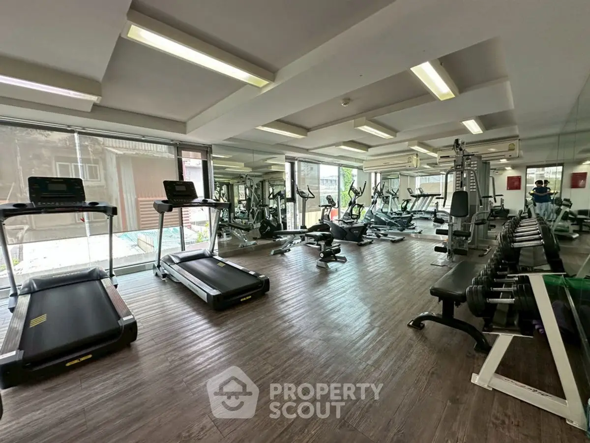 Spacious modern gym with state-of-the-art equipment and large windows for natural light.