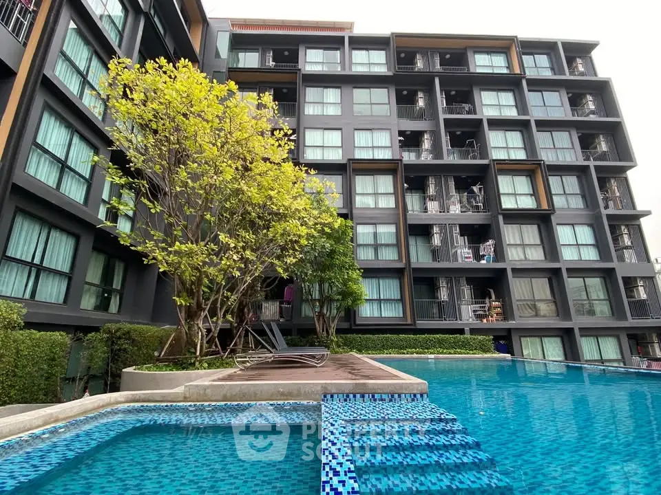 Modern apartment building with pool and lush greenery
