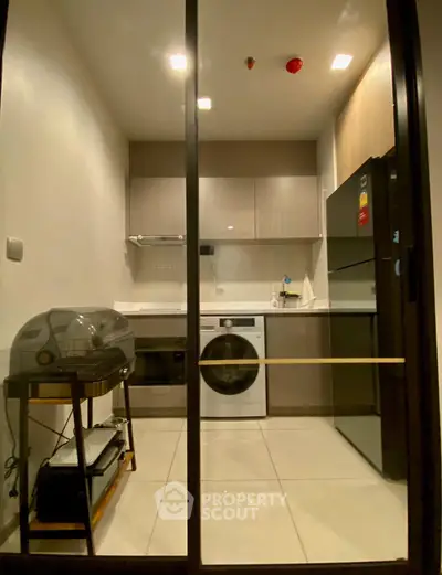 Modern kitchen with sleek appliances and washing machine in a compact layout.