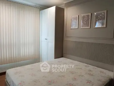 Cozy bedroom with floral bedding and elegant wall art, featuring a sleek white wardrobe and vertical blinds.