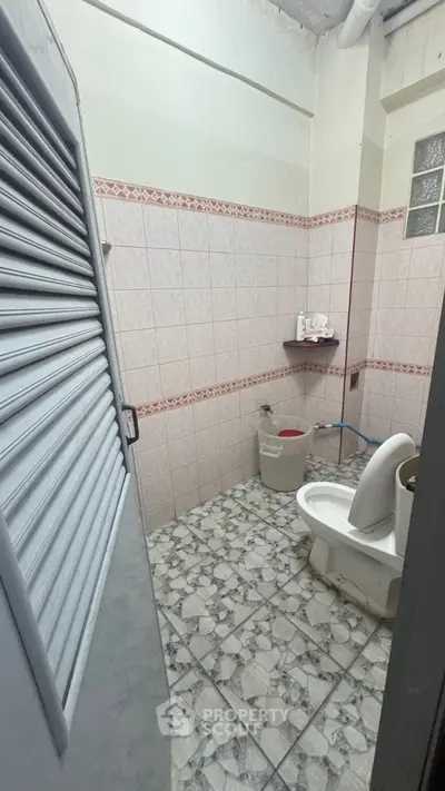 Functional bathroom with tiled walls and floor, featuring essential fixtures and a practical layout.