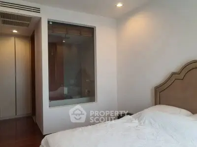 Modern bedroom with unique glass window to bathroom, featuring elegant design and cozy atmosphere.