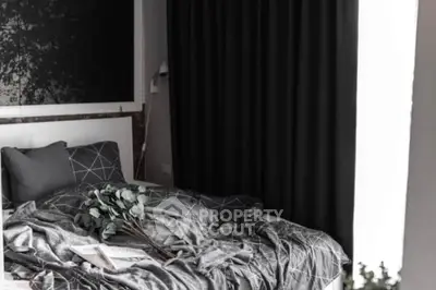 Cozy bedroom with modern decor and large window with dark curtains.