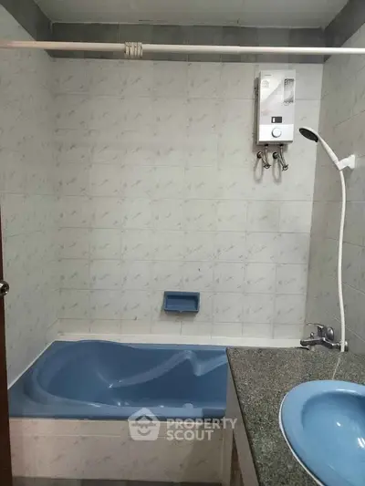 Cozy bathroom with blue bathtub and modern water heater, perfect for relaxation.