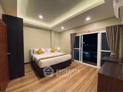 Spacious modern bedroom with elegant lighting and balcony access, perfect for relaxation and comfort.