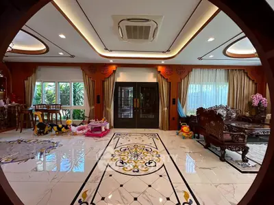 Luxurious living room with ornate ceiling and elegant furniture, featuring large windows and intricate floor design.