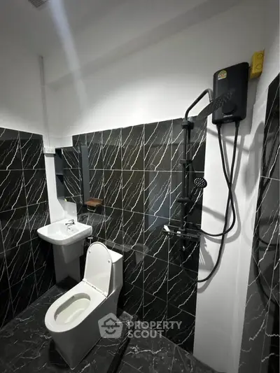 Modern bathroom with sleek black marble tiles and contemporary fixtures.
