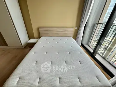 Modern bedroom with large window and city view, featuring a comfortable bed and sleek design.