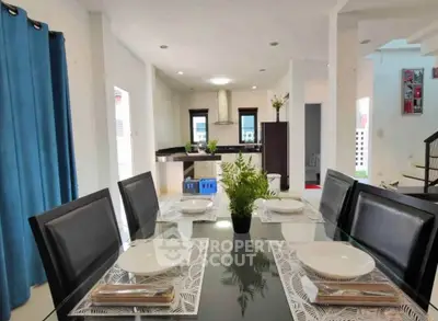 Modern dining area with elegant table setting and view into sleek kitchen