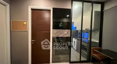 Modern apartment interior with kitchen and dining area featuring sleek design and glass partition.