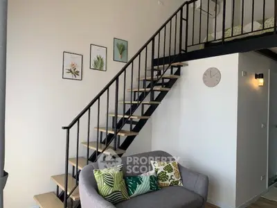Modern loft apartment with stylish staircase and cozy living area, featuring decorative wall art and a comfortable sofa.