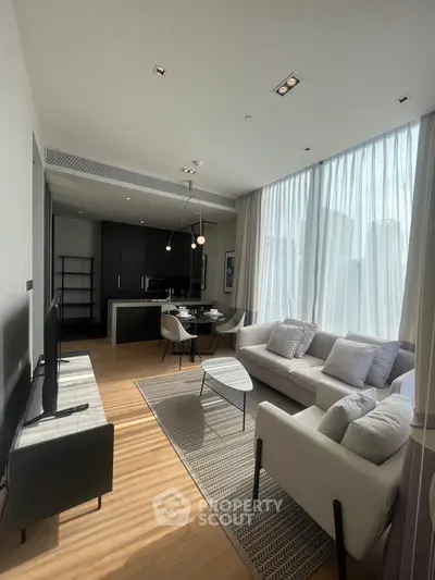Modern living room with open kitchen, stylish furniture, and large windows offering city views.