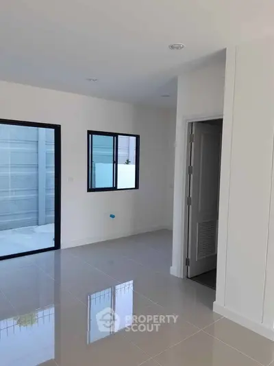 Modern minimalist interior with glossy tiled flooring and large windows for natural light.